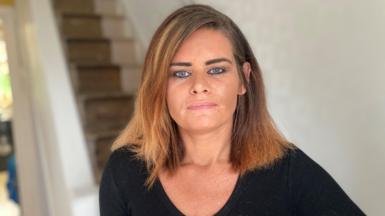 A woman with brown hair looks at the camera