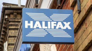Close-up image of a Halifax sign in blue and white, hanging off a traditional high street building.