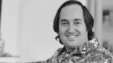Neil Sedaka in a black and white photo wearing a 1970s style shirt