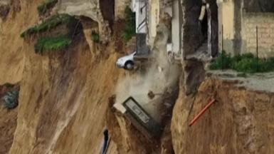 A car teetering on the edge of a drop after a landslide