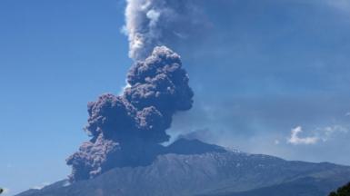 Large dark grey plumes are seen rising from Mount Etna