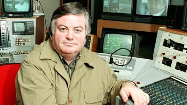 Roger Cook in a TV editing suite, wearing a khaki jacket 