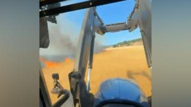 Tractor drives past burning field.