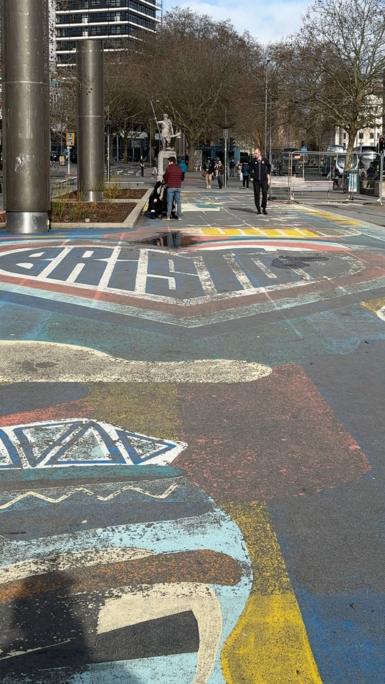 Faded street art on the ground, including the word Bristol in a heart.