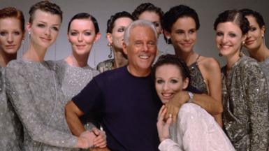 Giorgio Armani in front of a row of female models