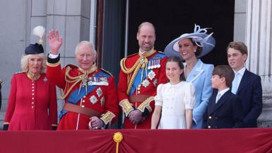 Members of the Royal Family stand on the Buckingham Palace balcony and wave. From left to right: Queen Camilla and the King, the Prince and Princess of Wales, and Princess Charlotte, Prince George and Prince Louis