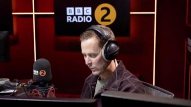 Scott Mills in a BBC Radio 2 studio, wearing headphones
