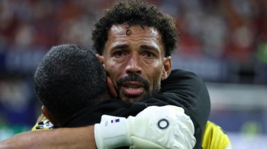 Vozinha hugging someone after the match against Spain with tears in his eyes.