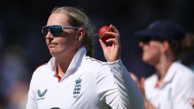 Sophie Ecclestone raises the match ball after taking five wickets v India