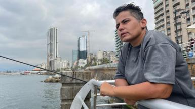 Hiba Maslkhi leaning on a fence at the Beirut waterfront.