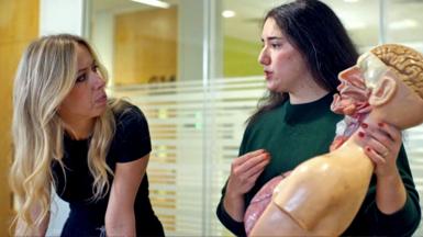 BBC Panorama presenter Catrin Nye stands next to Stephanie Metzger, who is holding a model of the human body.