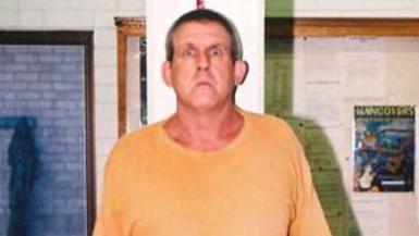 A man in a yellow t-shirt stares at the camera
