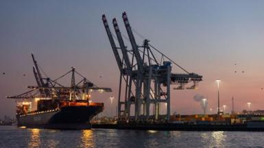 Cranes hover over a container ship with lights at dusk at the HHLA Container Terminal Tollerort (CTT) at the Port of Hamburg in Hamburg, Germany, on Monday, Feb. 3, 2025. 