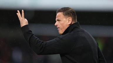 An angry-looking Richie Wellens holds three fingers up at his Orient players from the touchline