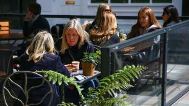 People sit at outdoor dining tables set up outside a restaurant at Covent Garden in London, UK