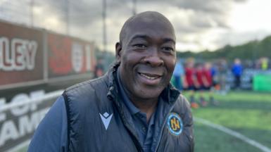 Man smiles at camera, he is wearing a dark jacket and shirt
