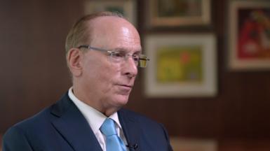 Blackrock CEO Larry Fink being interviewed. He is wearing a dark blue suit, white shirt and light blue tie