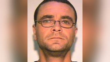 Andrew Malkinson with short brown hair, glasses and light stubble. The image was issued by police.