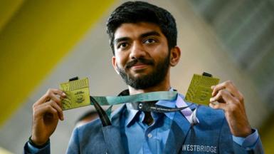 Gold medalist grandmaster Dommaraju Gukesh, shows his medals upon his arrival at the Chennai International Airport in Chennai on September 24, 2024, after his win at the 45th FIDE Chess Olympiad Budapest 2024. (