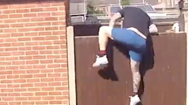 Man jumping over a garden fence.