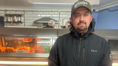 Co-owner of Môr Ffres, Rhys McLoughlin standing in front of the friers at the fish and chip shop in Dinas Cross, Pembrokeshire