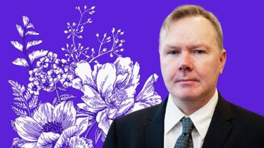 Sean Coughlan standing in front of a purple and floral background