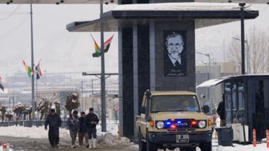 Scene at Iraqi border with Iran, as a vehicle and people pass through a crossing point in the snow