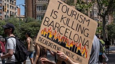A protester sign that reads "Tourism is killing Barcelona"