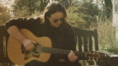 Y cerddor Melda Lois yn chwarae gitâr acwstig