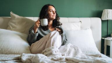 A woman in bed drinking a cup of tea