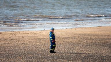 Rescuer on beach wears reflective clothing