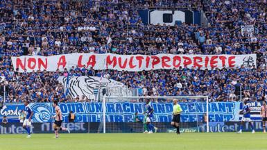 Strasbourg's ultras hold up a banner in protest at the club being part of a multi-club ownership structure