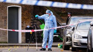 Police forensics team at the scene of the shooting behind a police cordon