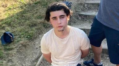 Daniel Khalife in a white t-shirt with his arms behind his back after being arrested