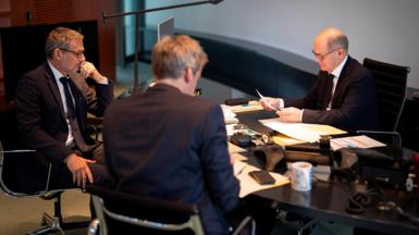 German Chancellor Olaf Scholz talks to Russian President Vladimir Putin on the phone as foreign and security policy advisor Jens Ploetner and government spokespokesman Steffen Hebestreit look on in around a table