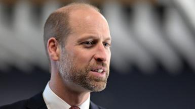 A close-up of Prince William, during a visit to Wales in December 2025. He is wearing a suit with a red tie. 