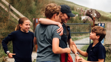 Charlotte looks at her mum who has an arm around George and is being held on the other arm by Louis who she smiles at 