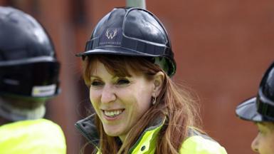 Angela Rayner grinning broadly as she wears a black hard hat and yellow high vis jacket