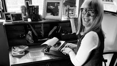 Yvette Fielding sat at the desk with the typewriter in a black and white image