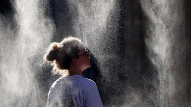 A woman cools off under a mist sprayer in Bordeaux, France.