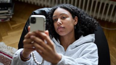 Young woman looks worried while looking at her smartphone