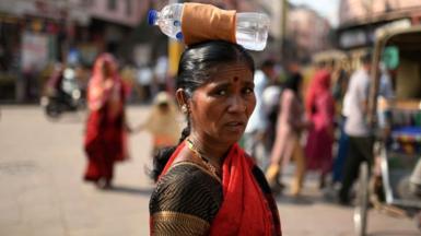 A woman is carrying a bottle of water on her head during a heatwave in Varanasi, India, on May 29, 2024.