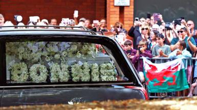 Crowds line the street as the funeral cortege passes.