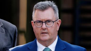 Sir Jeffrey Donaldson leaving Newry Crown Court. He has short grey hair, wearing glasses, a blue blazer, white shirt and light blue tie.