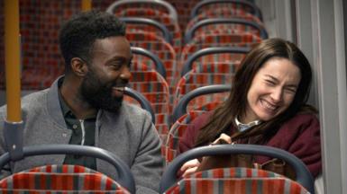 Paapa Essiedu and Siobhán Cullen sitting on the bus and laughing 