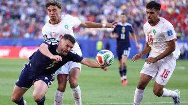 Scotland's John McGinn is challenged by Neil El Aynaoui