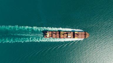 An aerial view of a container ship on a blue-green sea.