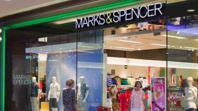 Two women walking in and out of a Marks and Spencer store