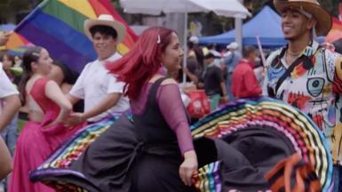 People dancing whilst wearing colourful rainbow clothing
