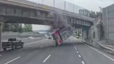 A tractor trailer is flipped over after hitting the overpass.